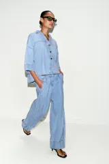 Jeans de tiro medio con corte wide leg y pinzas delanteras. Presenta bolsillos frontales, bolsillos de plastrón en la parte trasera, cierre frontal con cremallera, botón interior y ganchos metálicos.