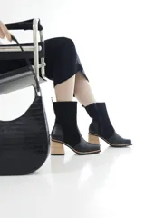 Bota de caña media combinada en cuero liso y descarne color marrón, con punta cuadrada, cierre lateral y taco ancho de madera.