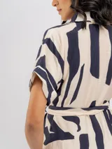 Vestido midi camisero de viscosa color beige con estampado abstracto en azul marino, manga corta, cuello camisero, cierre frontal con botones y lazo ajustable en la cintura.