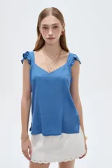 Musculosa amarilla de viscosa, con cuello en V y breteles anchos decorados con volados. Presenta un corte holgado.