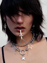 Collar plateado con cadena de eslabones y dijes colgantes de estrellas y esferas.