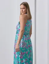 Vestido largo de gasa con estampado floral en tonos turquesa, rosa y verde. Tiene cuello halter cruzado, corte en la cintura con faja plisada y abertura en la espalda con cierre invisible.