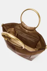 Bolso de hombro tipo mini saca con cuerpo en patchwork de denim en tonos azules. Posee una anilla metálica dorada como asa de mano y una correa bandolera extraíble.