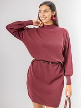 Vestido tipo polerón de tejido de punto color borgoña, con cuello alto, mangas largas con puños ajustados y corte recto. Incluye un cinturón del mismo material con una hebilla decorativa de flor con cristales.