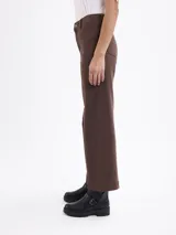 Pantalon de corte recto y ancho, color marrón, con costuras verticales decorativas en el frente y cierre de botón y cremallera.