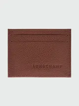 Tarjetero de cuero granulado color caramelo, con múltiples ranuras para tarjetas. Presenta el logo de Longchamp grabado en el centro.