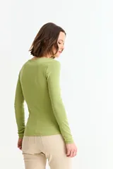 Remera de manga larga, color blanco, con tejido acanalado y escote cuadrado. Presenta un cierre metálico dorado en el centro del escote.