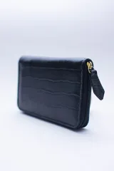 Billetera chica de cuero negro con textura tipo cocodrilo, cierre exterior, bolsillo para monedas con cierre en la parte trasera, múltiples ranuras para tarjetas y billetes, y forro rojo.