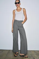 Jeans wide leg de tiro alto y diseño relaxed fit, confeccionados en denim azul marino con patrón de rayas verticales blancas. Cuenta con cinco bolsillos, cierre frontal con cremallera y botón, y detalle de nervio delantero con pespuntes a contraste.