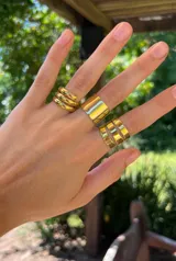 Anillo dorado ancho con tres bandas horizontales separadas por finas líneas.