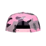 Gorro estilo snapback Supreme x New Era, modelo 59Fifty, con estampado de camuflaje en tonos rosa, morado y negro. Presenta el logo estilizado de los Chicago White Sox en negro y blanco en el frente y el logo de Supreme bordado en la visera.