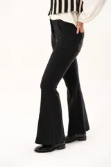 Pantalón de vestir negro de corte acampanado, con cintura de tiro medio, cierre frontal con botón y bolsillos laterales.