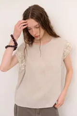 Blusa de lino color blanco con detalles de crochet en tono verde militar en los hombros, cuello redondo y manga corta.