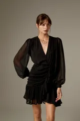 Vestido corto negro de poliéster, con escote en V cruzado, mangas largas abullonadas con puños ajustados y detalle de lazo en la cintura.