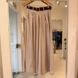 Pantalón ancho color beige de tiro alto, con pinzas delanteras y diseño fluido.