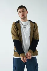 Campera de felpa de diseño color block en tonos marrón y negro, con capucha con cordón ajustable, cierre frontal y bolsillos. Presenta lettering estampado en el pecho.