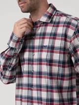 Camisa de manga larga para hombre, con estampado de tartán en tonos blanco, rojo y azul marino. Presenta cuello clásico, cierre frontal abotonado y un bolsillo en el pecho con el logo de la marca bordado.