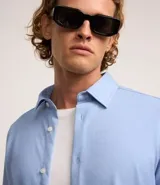 Camisa de manga larga blanca, corte slim fit, con cuello tradicional y abotonadura frontal.