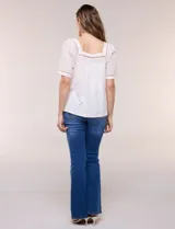 Blusa de corte holgado color marfil, confeccionada en mezcla de modal y algodón, con escote cuadrado y mangas cortas adornadas con detalles de puntilla calada.