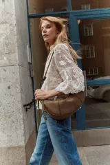 Jeans de tiro alto en denim de algodón rígido, color azul medio con efecto degradado (ombré) que se oscurece hacia el bajo. Corte acampanado (flare) y bajo deshilachado. Presenta bolsillos parche con botón en la parte delantera y trabillas ajustables con botón a los lados de la cintura.