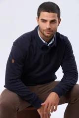 Buzo de felpa color verde oscuro, con cuello tipo polo, cierre frontal parcial con botones y bolsillos laterales. Presenta puños y ruedo acanalados.