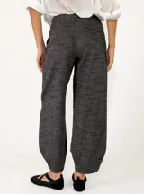Pantalón azul marino de tiro alto y corte ancho, confeccionado en tejido con textura sutil, bolsillos laterales y cierre frontal con botón.