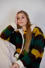 Chaqueta a cuadros color marrón, verde y amarillo, con cuello y puños de corderito sintético. Tiene cierre frontal con botones y bolsillos laterales.