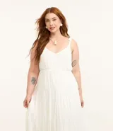 Vestido midi blanco confeccionado en tejido de viscosa con hilo metalizado, breteles finos de moña, escote v, busto marcado y volados en la pollera.