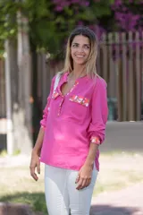 Camisa fucsia de viscosa con detalles pintados a mano en cobre, rosa y blanco en cuello, bolsillos y puños. Presenta mangas largas, cuello en V con escote abotonado y bolsillos frontales con solapa.