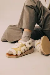 Sandalias con plataforma de madera y tiras de cuero color dorado con borde de corderito blanco.