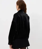Campera bomber de poliuretano texturizado en color negro, con cuello camisero, cierre frontal, bolsillos aplicados en el pecho y ruedo elástico.