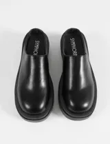 Zuecos negros de cuero sintético con plataforma gruesa y suela track dentada.