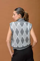 Chaleco tejido sin mangas con cuello alto, diseño de rombos en tonos grises y detalles de hilo lurex brillante.