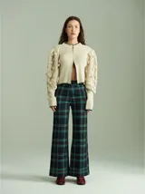 Pantalón de tiro alto con corte ancho y recto, confeccionado en tela de algodón con estampado de cuadros escoceses en tonos azul marino, verde y rojo. Presenta cierre frontal oculto con botones internos y pasacintos en la cintura.