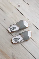 Sandalias bajas color verde oliva, con dos tiras anchas cruzadas sobre el empeine y tira trasera con hebilla.