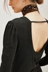 Remera de viscosa en color beige, de manga larga con detalle de frunces en los hombros y un pronunciado escote en la espalda con tira horizontal.