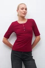 Remera verde de tejido canalé con cuello redondo y media manga. Tiene una abertura frontal con botones.