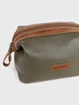 Neceser de cuero texturizado color verde oliva, con detalles en cuero color suela en los bordes y tiradores de cierre. Cuenta con cierre superior y etiqueta de cuero con logo grabado en el frente.