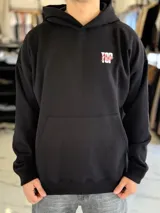 Canguro negro de corte oversize con capucha, manga larga y bolsillo tipo canguro al frente. En la espalda presenta un gran estampado gráfico con las palabras "Top Style" en blanco y rojo, acompañado de inscripciones y detalles minimalistas.