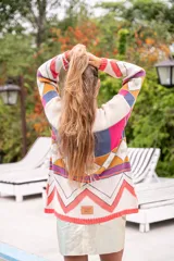 Sweater de punto con diseño geométrico multicolor y cuello redondo. El borde del cuello, puños y ruedo es de color salmón fluorescente.