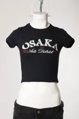 Remera baby tee de morley color chocolate, de calce ajustado al cuerpo y manga corta, con cuello redondo y diseño estampado frontal.