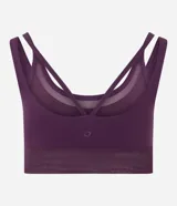 Top deportivo de microfibra color violeta con diseño de doble bretel y detalle de superposición con tul en el escote. Incluye copas removibles para mayor soporte.