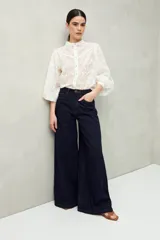 Jean de mezclilla color azul oscuro, tiro alto y calce ultra wide leg (pierna muy ancha y fluida). Diseño clásico de cinco bolsillos con cierre de botón y cremallera.