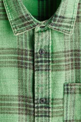 Camisa H&M de sarga de algodón verde con diseño de cuadros oscuros, cuello inglés, un bolsillo en el pecho y cierre frontal de botones.