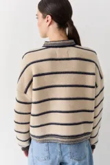 Cardigan de punto color bordó con cuello redondo, cierre frontal de botones y detalles de ribetes en contraste en cuello, puños y ruedo. Presenta un pequeño bordado de una raqueta de tenis en el pecho.