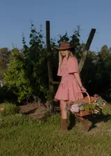 Vestido corto de color blanco con cuerpo fruncido tipo nido de abeja, cuello alto con volados y mangas cortas amplias con vuelo.
