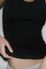 Top negro de corte ajustado (slim fit) con escote redondo y manga sisa.