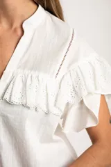 Blusa blanca de algodón con cuello mao, cierre frontal de botones y volados en los hombros con detalle de bordado inglés.