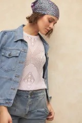 Top sin mangas de color rosado, confeccionado en tejido de punto de algodón con diseño de calados y cuello redondo.