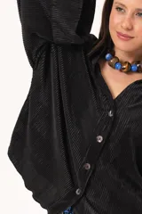 Camisa negra plisada de manga larga con puños vueltos, cuello camisero y cierre frontal de botones claros.